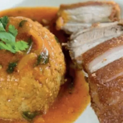 Mofongo in a garlic sauce beside sliced crisp-skinned pernil