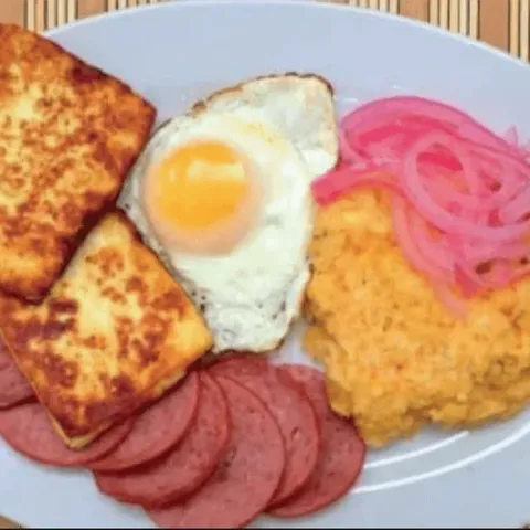 Mangú with pickled red onion, a fried egg, fried cheese and salami